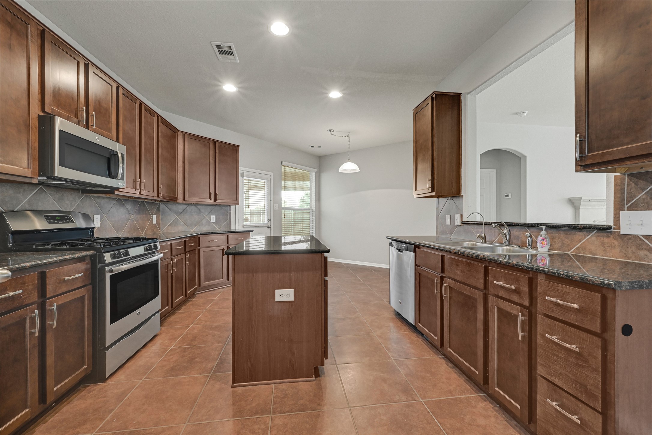 5331 Seabird Street Baytown, TX 77521 - Photo 19 of 38 a large kitchen with stainless steel appliances wooden cabinets and a stove top oven