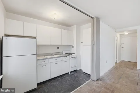 a kitchen with a refrigerator a stove top oven and white cabinets