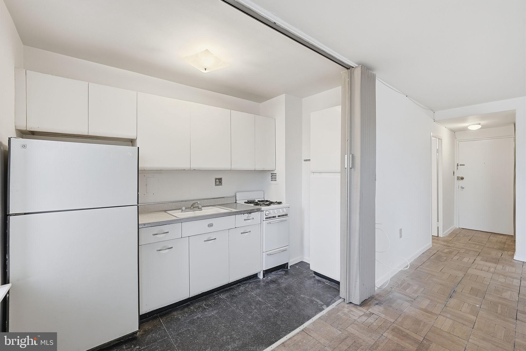 4100 W Street Northwest, Unit 203 Washington, DC 20007 - Photo 10 of 18 a kitchen with a refrigerator a stove top oven and white cabinets
