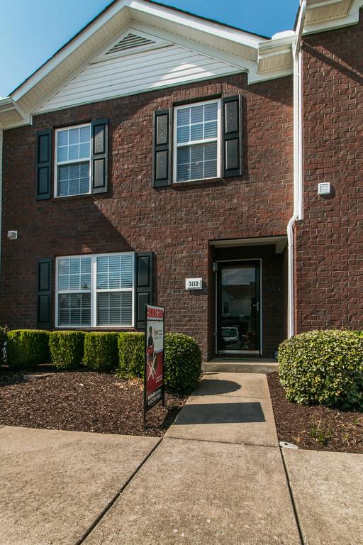 a front view of a house with a yard and potted plants