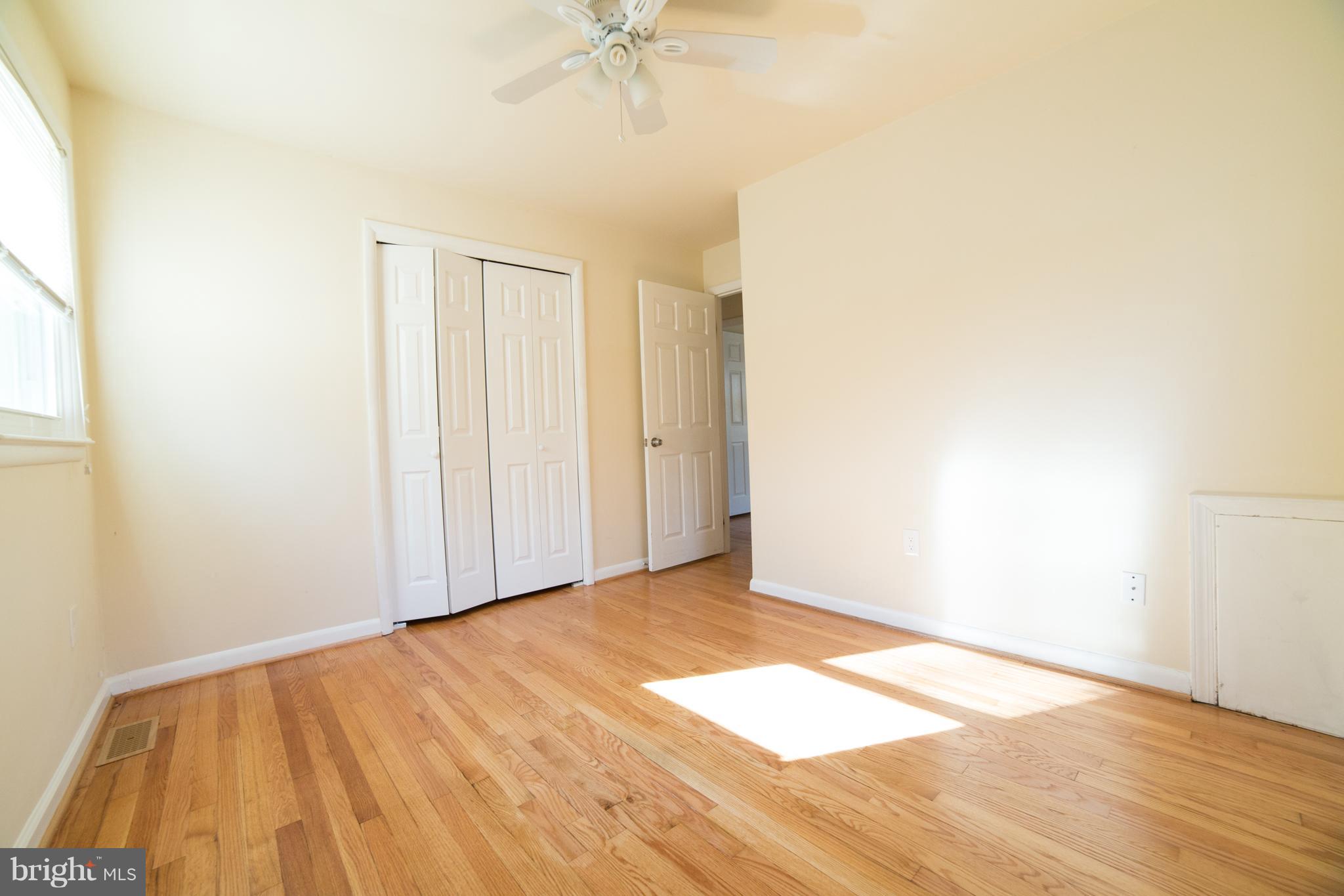 7106 Calamo Street Springfield, VA 22150 - Photo 14 of 30 a view of an empty room with wooden floor and a window