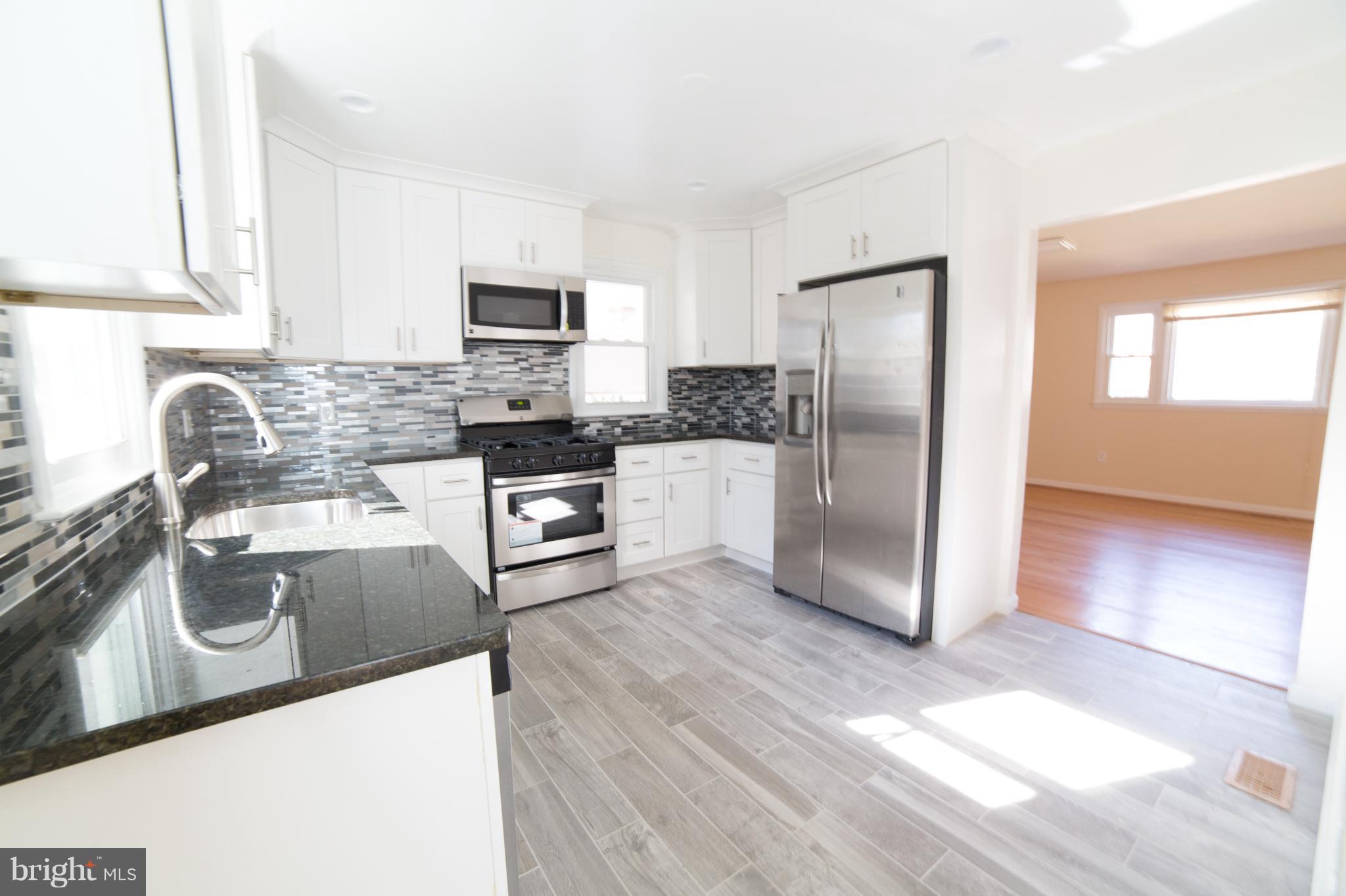 7106 Calamo Street Springfield, VA 22150 - Photo 6 of 30 a kitchen with stainless steel appliances granite countertop a refrigerator stove and sink
