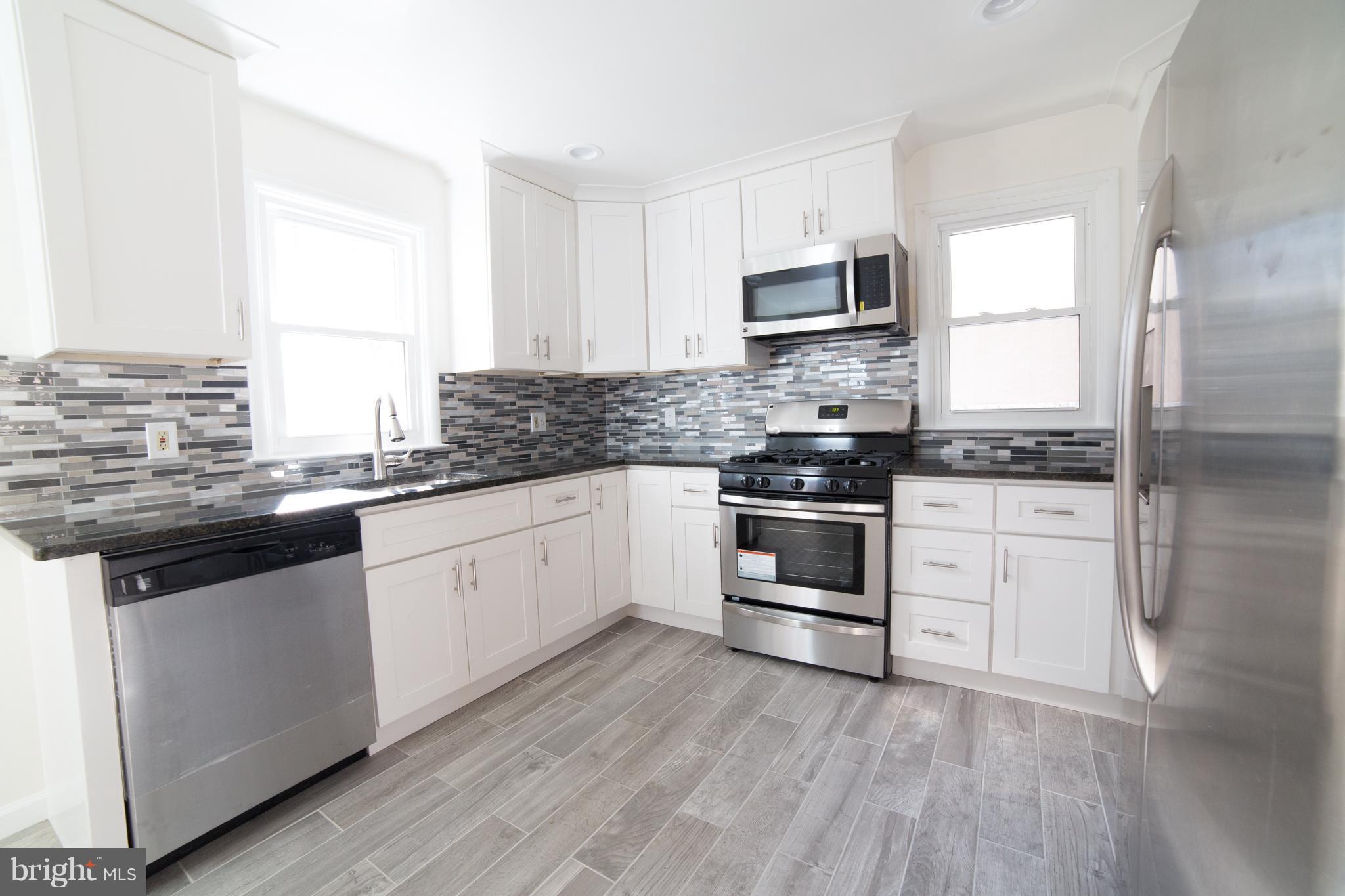 7106 Calamo Street Springfield, VA 22150 - Photo 7 of 30 a kitchen with granite countertop white cabinets and stainless steel appliances