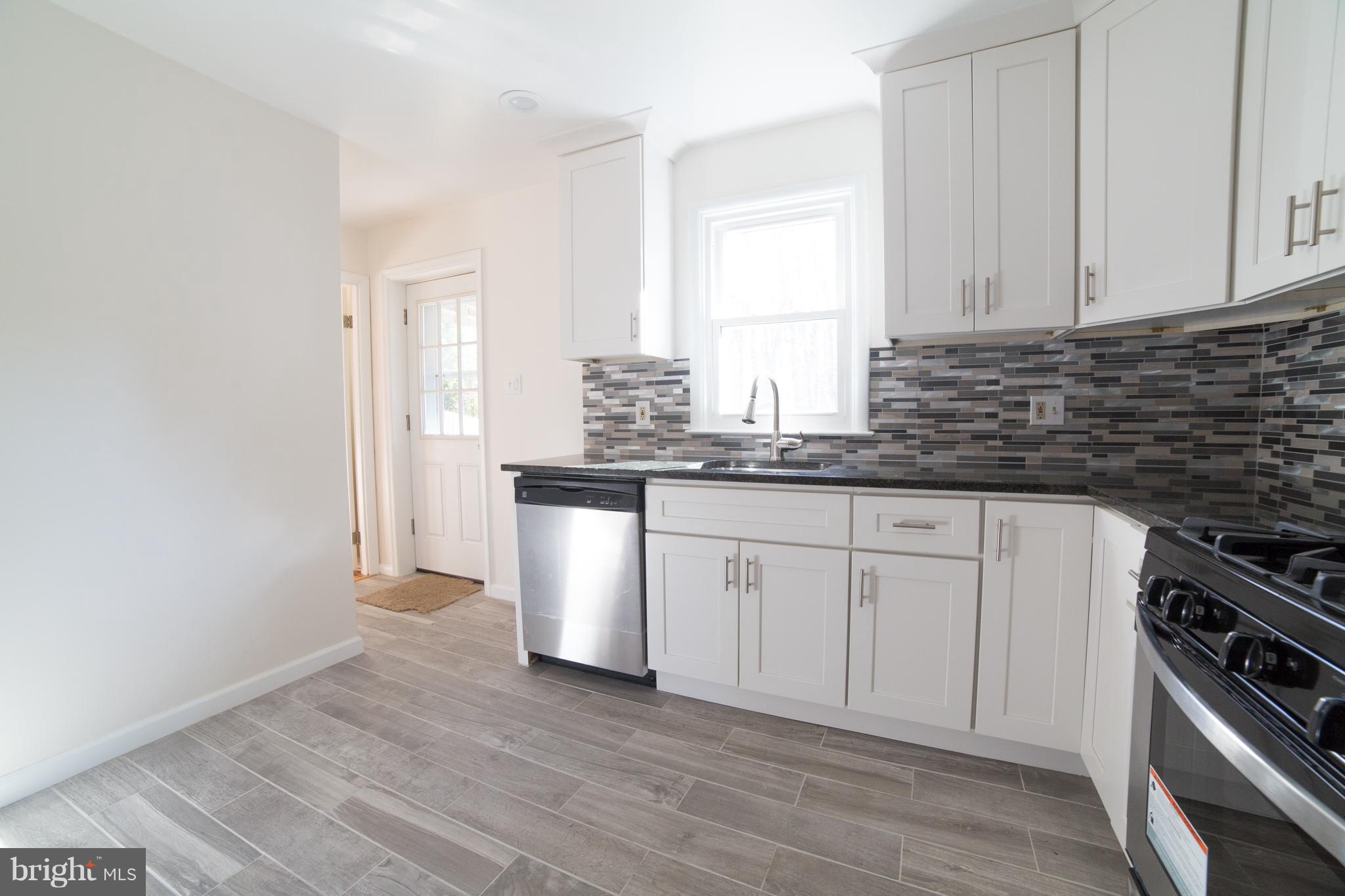 7106 Calamo Street Springfield, VA 22150 - Photo 8 of 30 a kitchen with stainless steel appliances granite countertop a sink a stove a microwave and cabinets