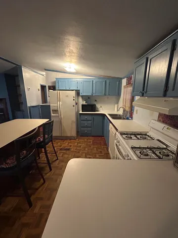 a kitchen with stainless steel appliances granite countertop a stove a refrigerator a sink dishwasher a dining table and chairs with wooden floor