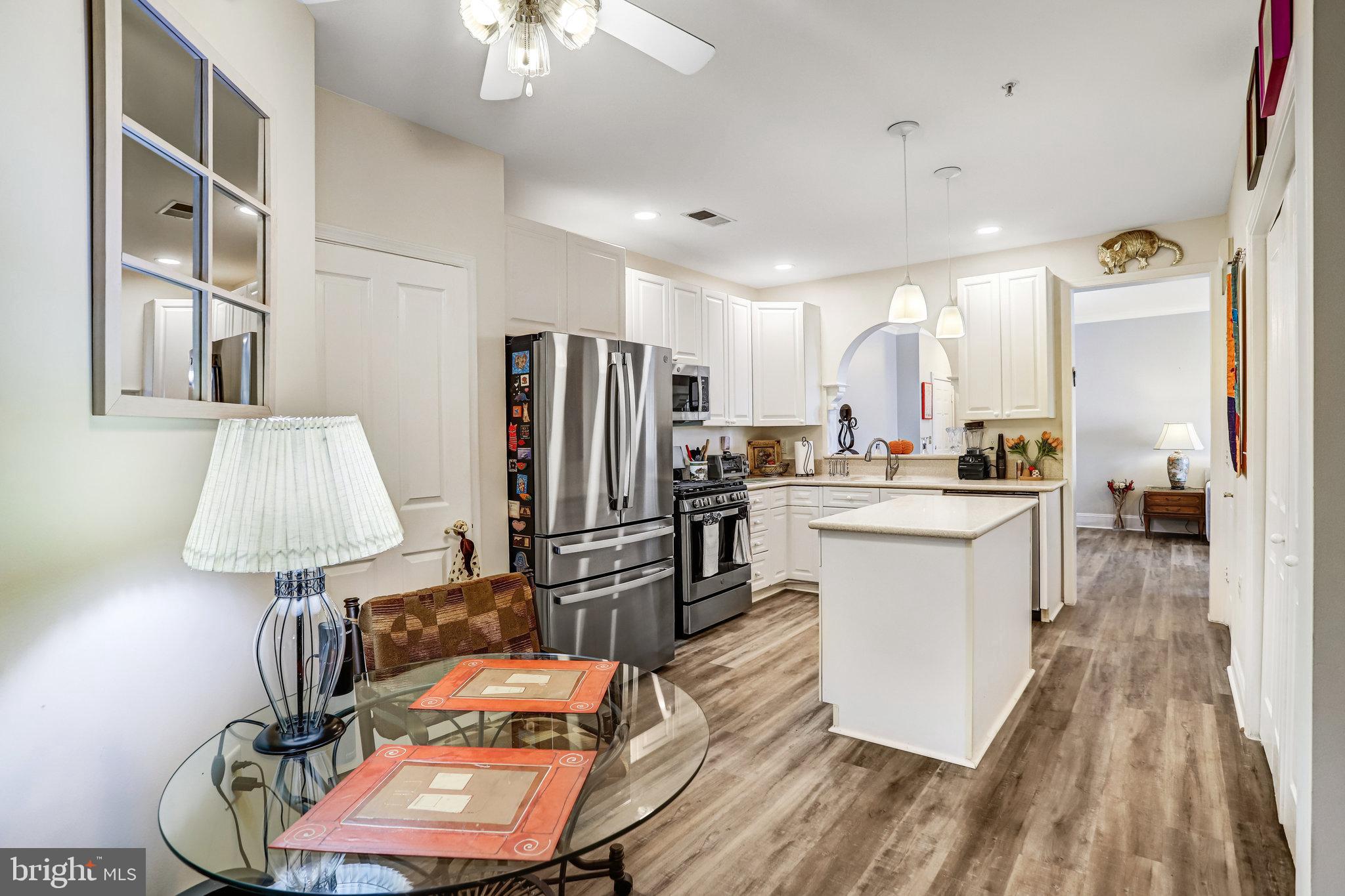 2500 Waterside Drive, Unit 303 Frederick, MD 21701 - Photo 14 of 47 a kitchen with stainless steel appliances a refrigerator a stove a sink dishwasher and a dining table with wooden floor