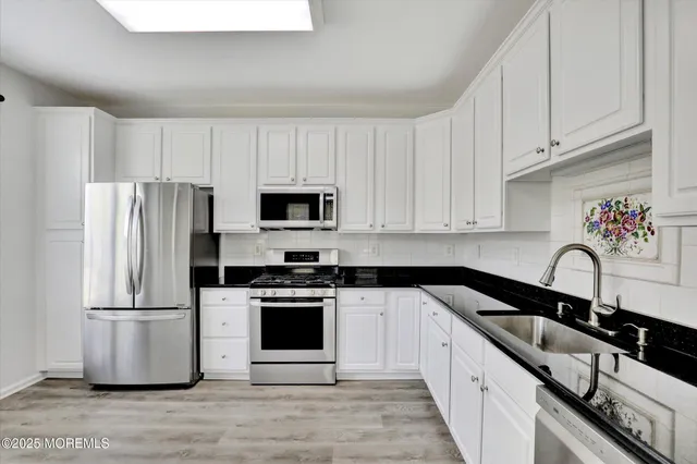 a kitchen with a refrigerator stove and white cabinets