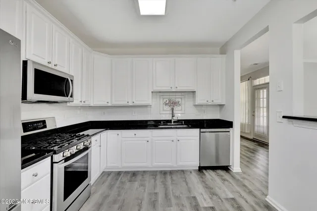 a kitchen with granite countertop a sink a stove and microwave