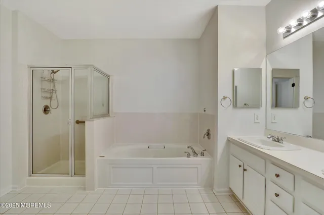 a spacious bathroom with a tub sink shower and a mirror