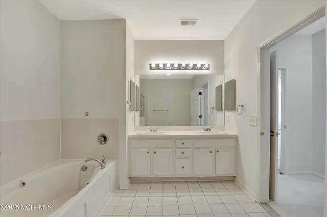 a spacious bathroom with a bathtub sink and mirror