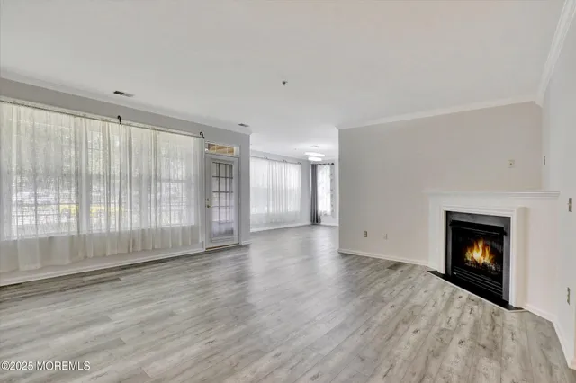 a view of an empty room with wooden floor fireplace and a window