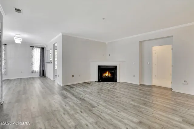 a view of an empty room with wooden floor and a fireplace