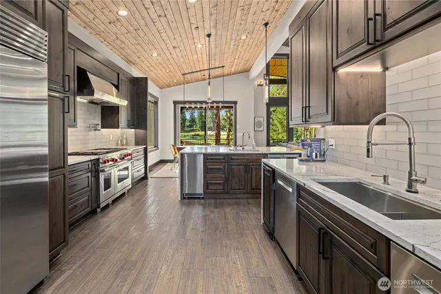 a kitchen with stainless steel appliances granite countertop a sink a stove and a wooden floors