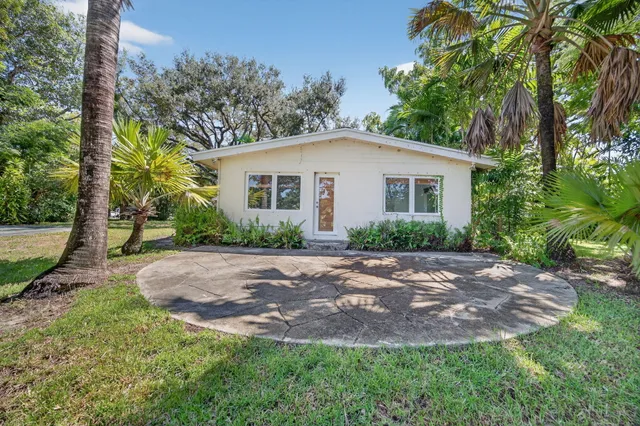 a view of white house with a yard and large trees