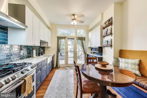 a kitchen with stainless steel appliances granite countertop a stove top oven a dining table and chairs with wooden floor