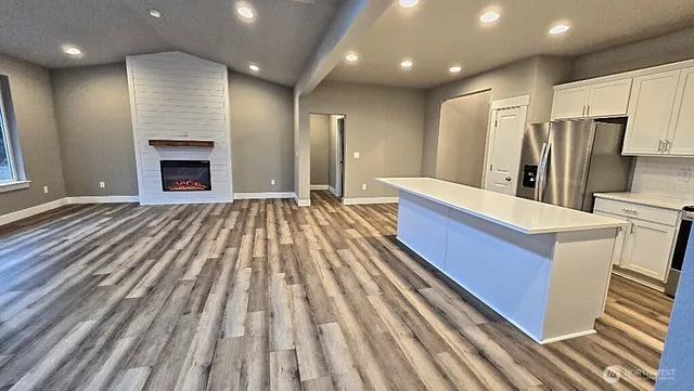 a large kitchen with a sink a refrigerator and a fireplace