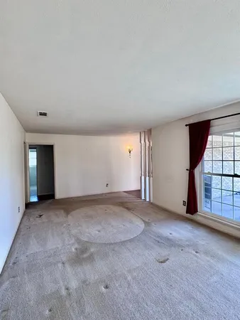 an empty room with windows and chandelier fan