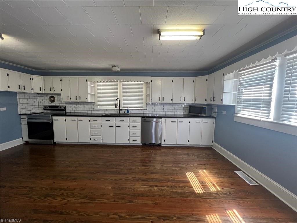 820 Suncrest Orchard Road North Wilkesboro, NC 28659 - Photo 23 of 41 a large kitchen with stainless steel appliances granite countertop a stove a sink dishwasher and white cabinets with wooden floor