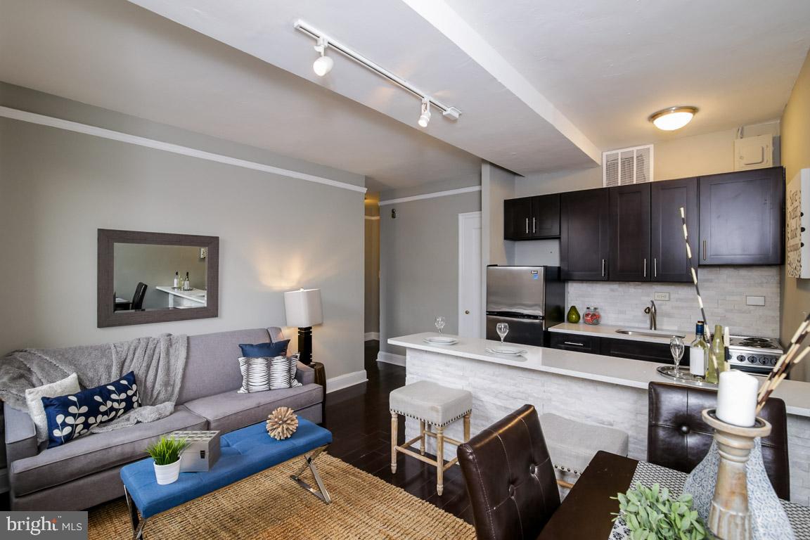 a living room with furniture kitchen view and a wooden floor