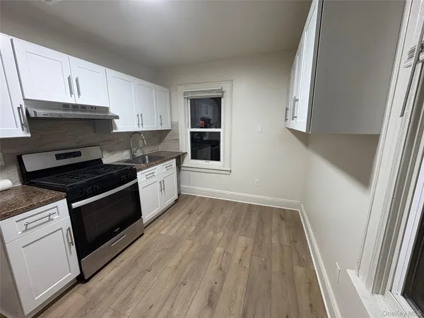 a kitchen with granite countertop wooden floors and white stainless steel appliances