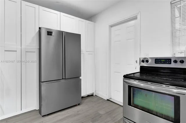 a kitchen with white cabinets and appliances