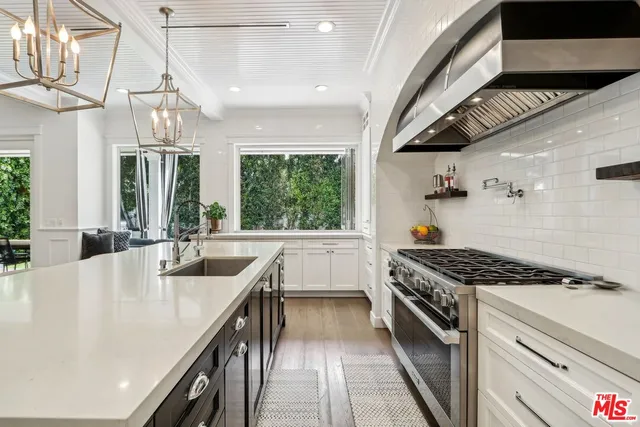 a kitchen with kitchen island stainless steel appliances a stove a sink dishwasher and cabinets with wooden floor