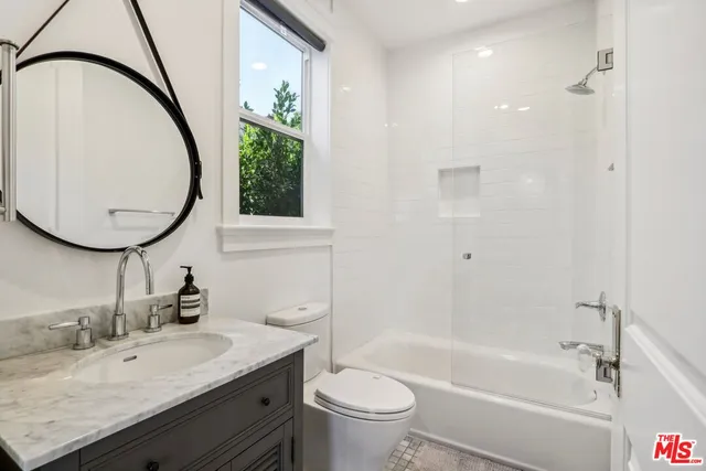 a bathroom with a granite countertop toilet a sink and a mirror