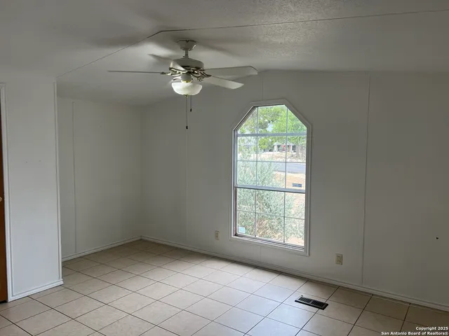 en empty room with windows and ceiling fan