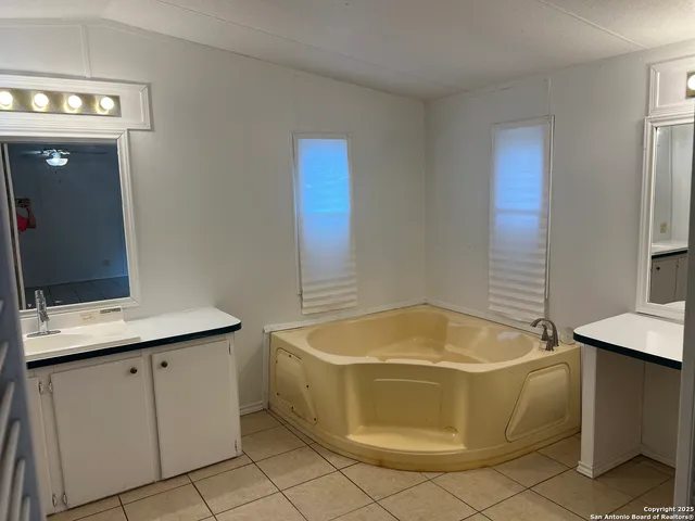 a bathroom with a tub sink vanity and mirror