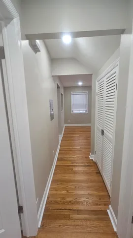 a view of a hallway with wooden floor and a bathroom