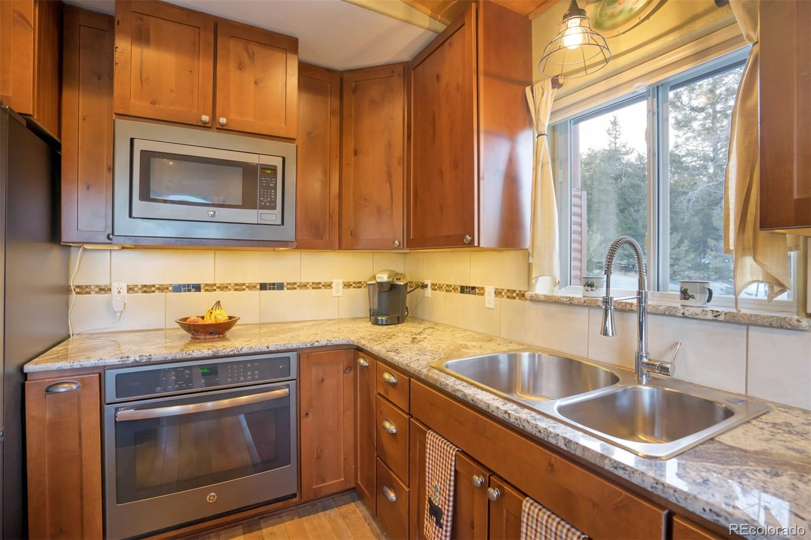 10424 Ranch Road Hartsel, CO 80449 - Photo 6 of 31 a kitchen with granite countertop a sink stove and microwave