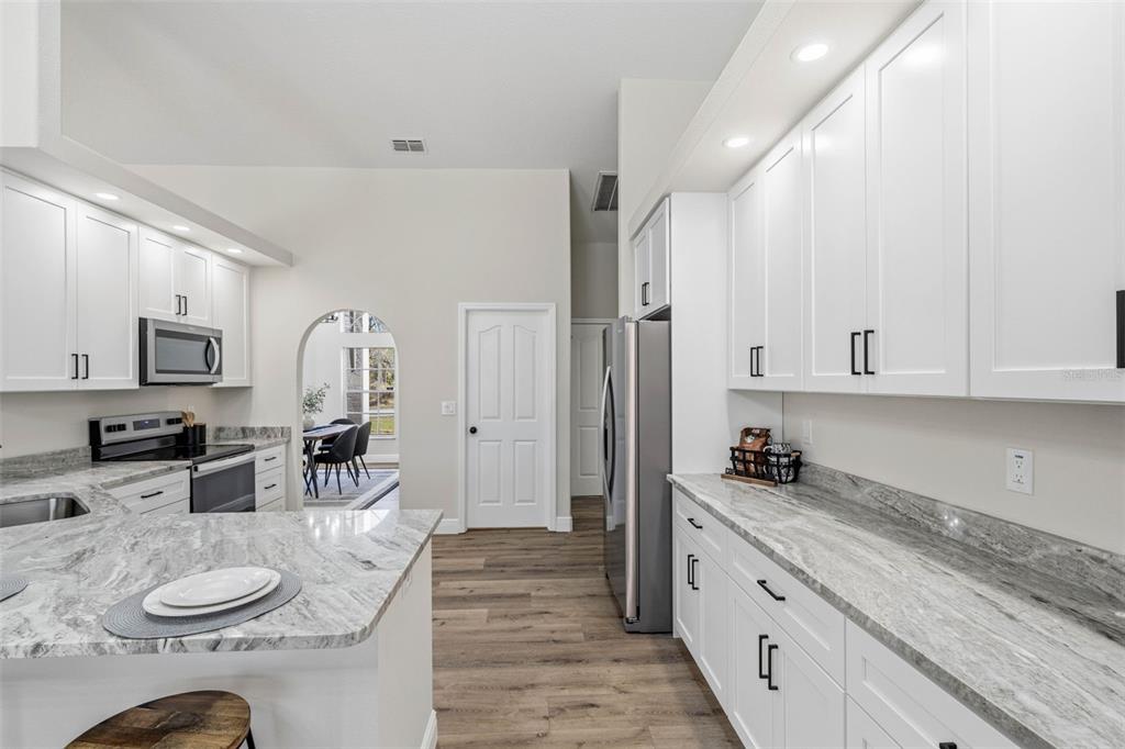 10185 Sleepy Willow Court Spring Hill, FL 34608 - Photo 16 of 44 a kitchen with stainless steel appliances kitchen island granite countertop a sink a stove a dining table and chairs