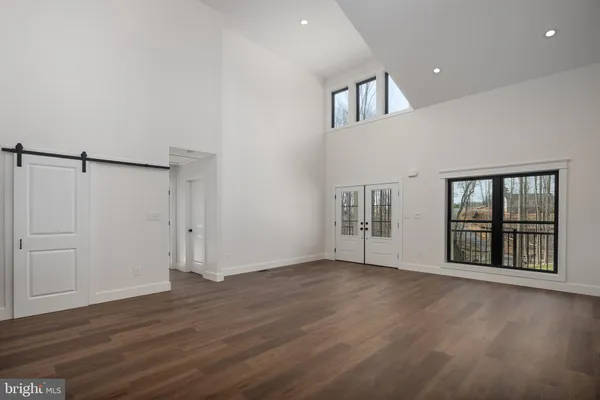 an empty room with wooden floor fire place and windows