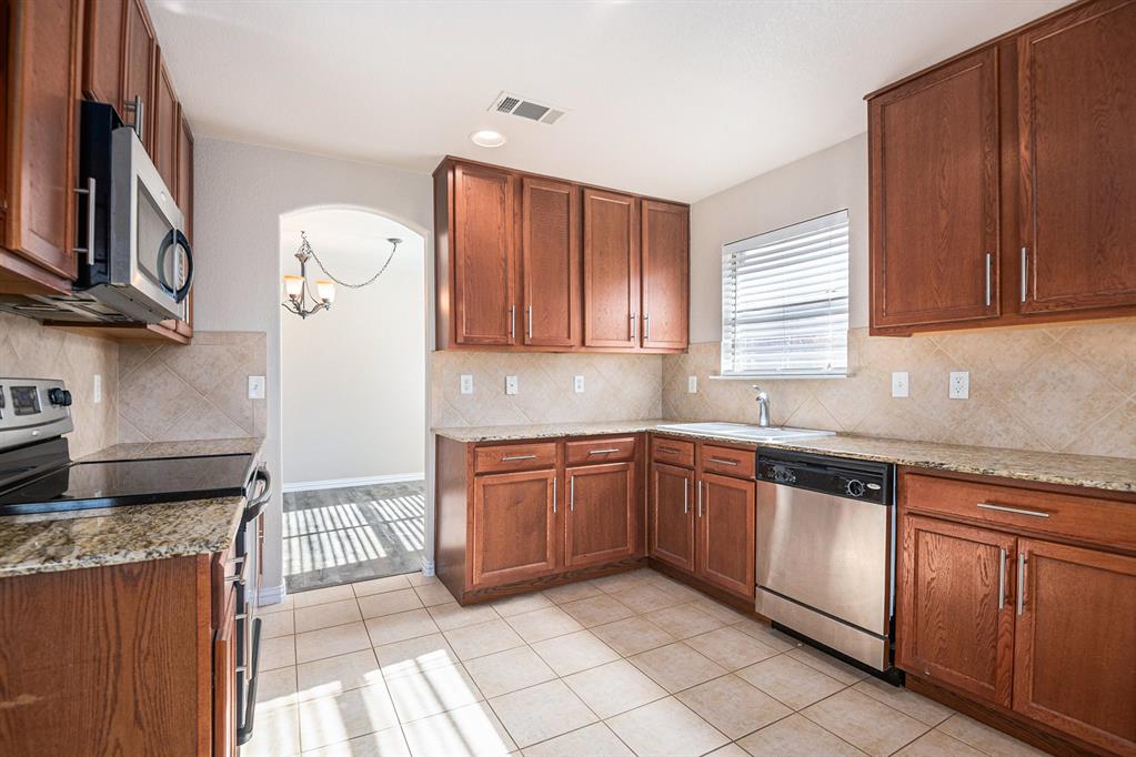 8313 Water Buck Run Fort Worth, TX 76179 - Photo 11 of 25 a kitchen with granite countertop stainless steel appliances a sink window and cabinets