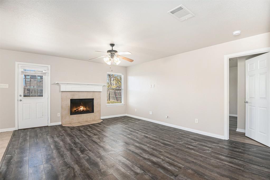 8313 Water Buck Run Fort Worth, TX 76179 - Photo 5 of 25 an empty room with wooden floor a fireplace and windows