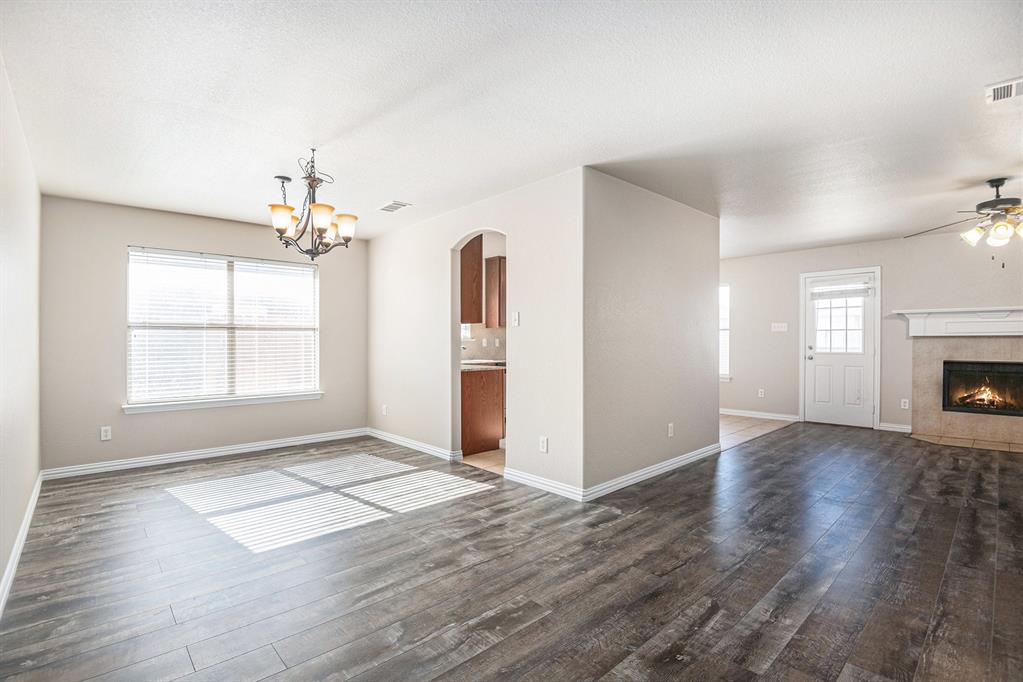 8313 Water Buck Run Fort Worth, TX 76179 - Photo 7 of 25 an empty room with wooden floor chandelier and windows