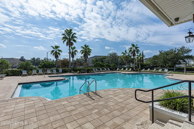 a view of swimming pool with seating space and trees in the background