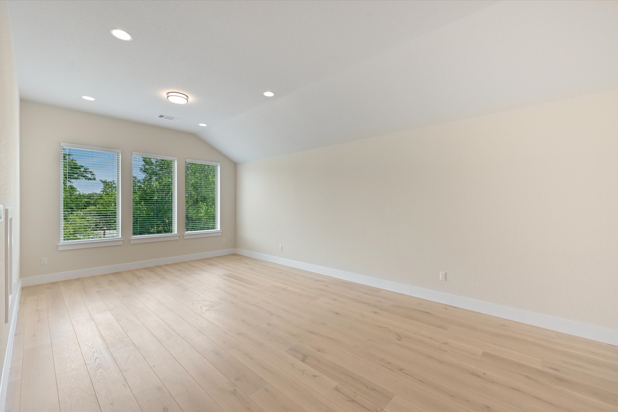913 Presa Arriba Road Austin, TX 78733 - Photo 15 of 30 A naturally illuminated room features vaulted ceilings and light-toned hardwood flooring, creating an inviting blank canvas.