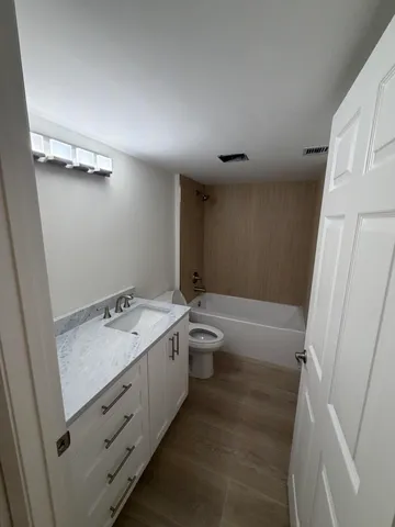 a bathroom with a granite countertop sink toilet and shower