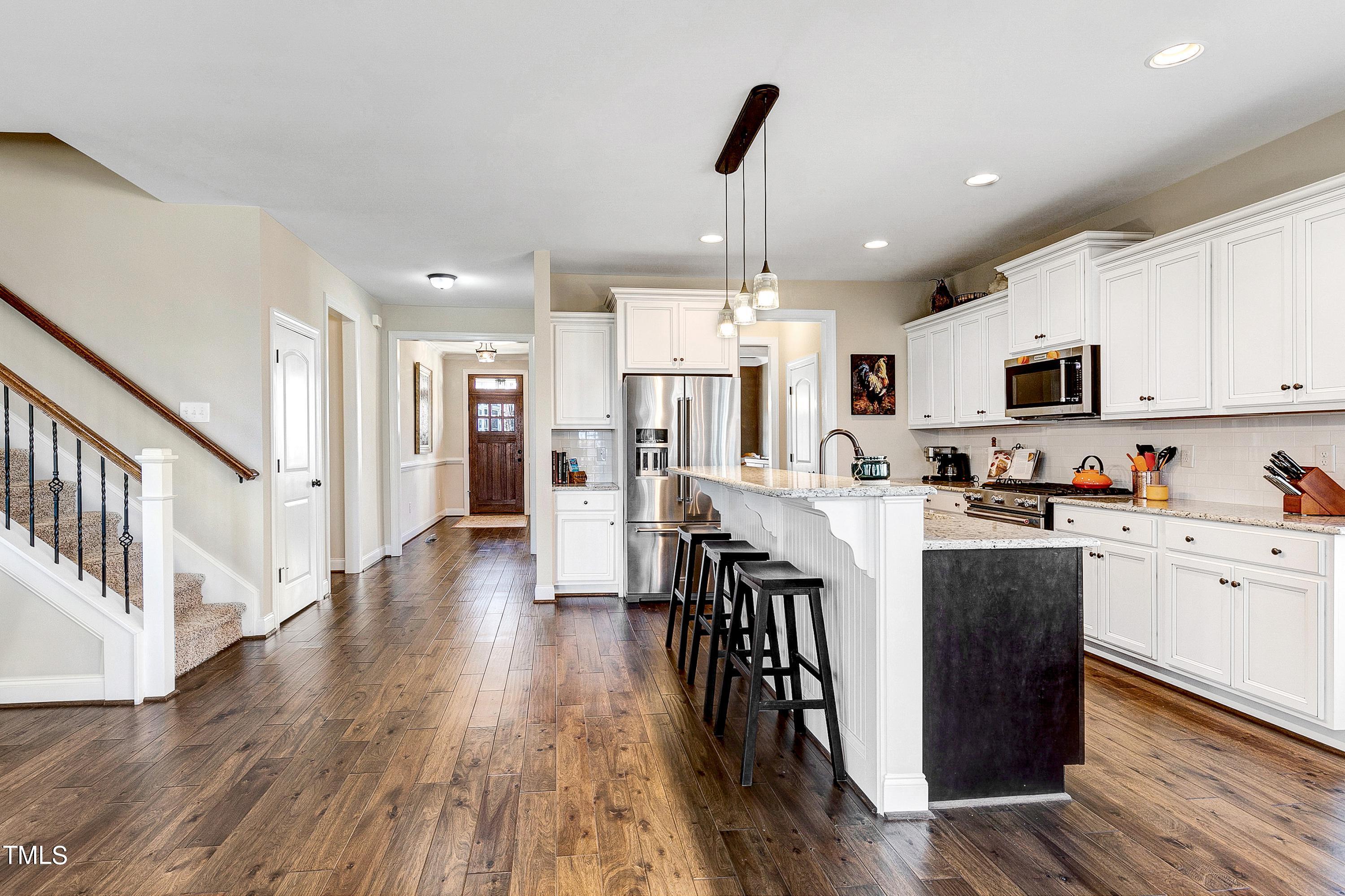 8533 Hurst Drive Raleigh, NC 27603 - Photo 10 of 43 a kitchen with stainless steel appliances kitchen island granite countertop a refrigerator a stove top oven a sink dishwasher and white cabinets with wooden floor