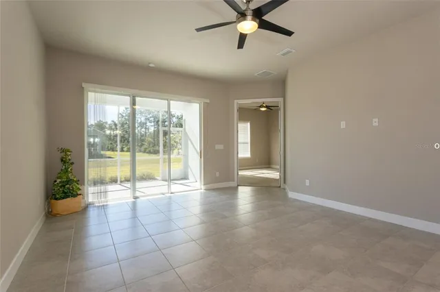 an empty room with floor to ceiling windows and a ceiling fan