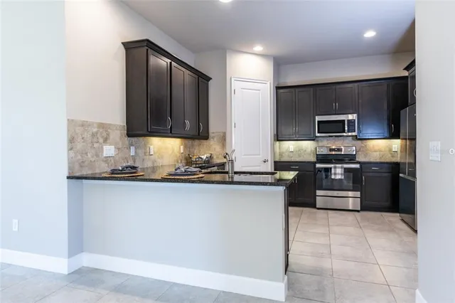 a kitchen with granite countertop a refrigerator and a stove top oven