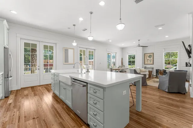 a kitchen with stainless steel appliances granite countertop a sink a stove a refrigerator and island with wooden floor