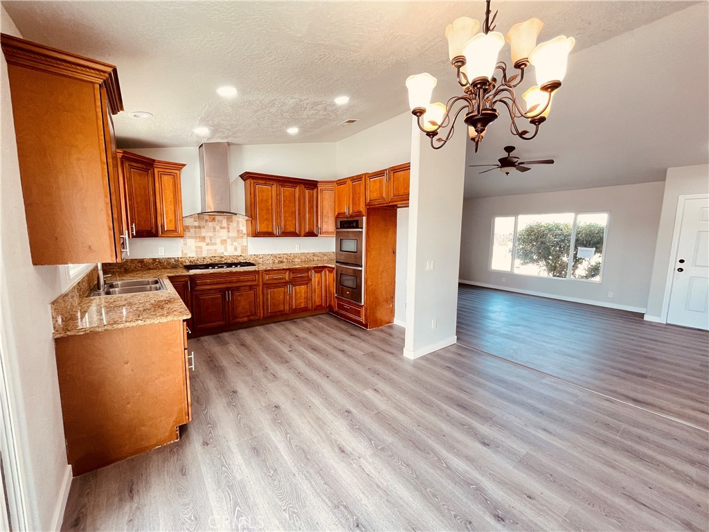 20891 Thunderbird Road Apple Valley, CA 92307 - Photo 17 of 45 a kitchen with stainless steel appliances granite countertop a refrigerator a stove and a wooden floors