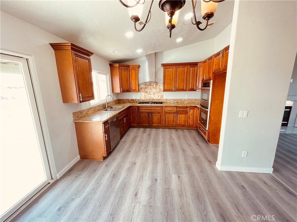 20891 Thunderbird Road Apple Valley, CA 92307 - Photo 18 of 45 a kitchen with a refrigerator a sink and wooden floor