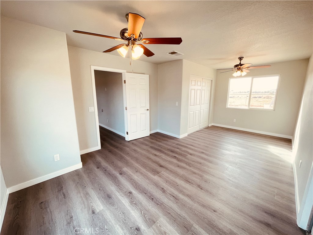 20891 Thunderbird Road Apple Valley, CA 92307 - Photo 24 of 45 an empty room with wooden floor ceiling fan and windows