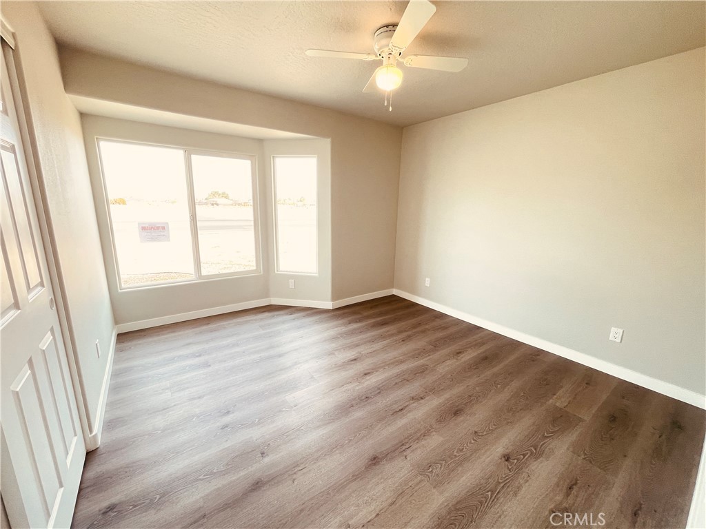20891 Thunderbird Road Apple Valley, CA 92307 - Photo 30 of 45 an empty room with wooden floor and windows