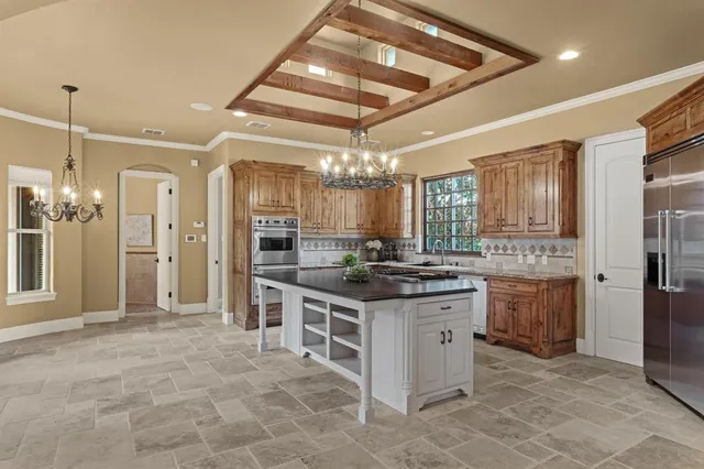 a kitchen with stainless steel appliances granite countertop a stove a refrigerator and a chandelier