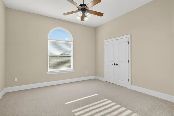 an empty room with windows and fan