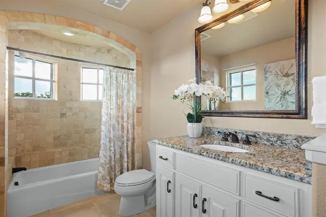 a bathroom with a granite countertop sink a toilet a mirror a bathtub and shower